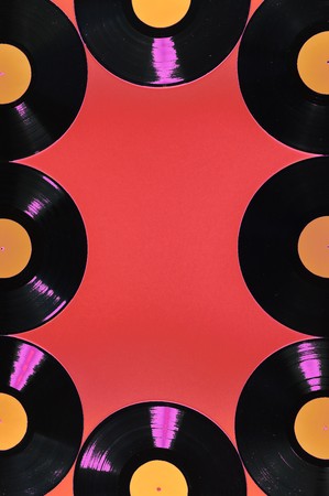 Old black vinyl records with blank orange labels on red background as frameの写真素材
