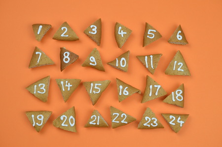 twenty-four numbered and sorted advent cookies on orange backgroundの写真素材