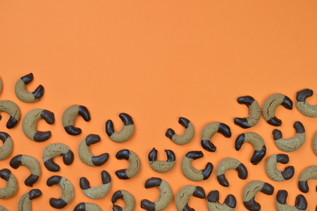 border out of home made nougat crescents cookies with chocolate at the edges and copy space above on orange backgroundの写真素材