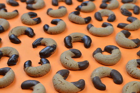 home made nougat crescents cookies with chocolate at the edges on orange backgroundの写真素材