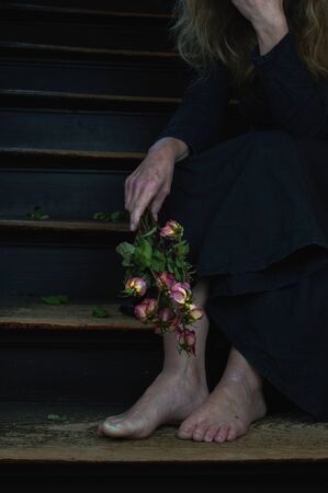 dead roses and woman in black linen dress as a symbol for divorce or a weeping widowの写真素材