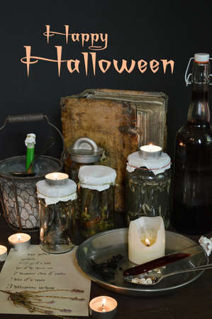 eerie witches' kitchen with lot of ingredients for a love potion and ancient gruesome jars dark with only candlelight for Halloweenの写真素材