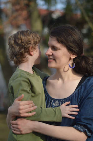 Happy mother holding little child in her arms with love in a garden outdoors in summertimeの写真素材