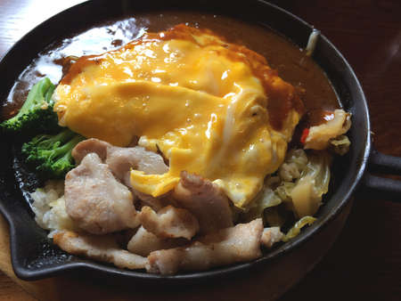 omurice with pork, broccoli and Japaese curry sauce on the hot place / Japanese traditonal foodの写真素材