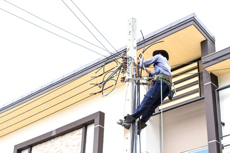 Electrician connects wires on a poleの写真素材
