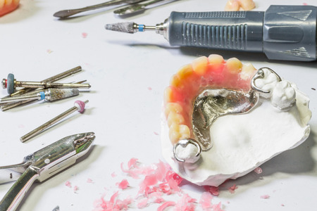 Partial denture with tool on table of dental technician workplace.