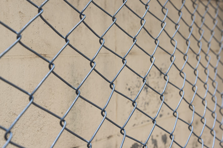 Fence from steel mesh on grunge cement wall backgroudの写真素材
