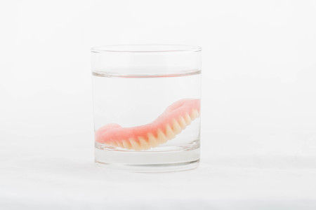 dentures in glass of water on white backgroundの写真素材