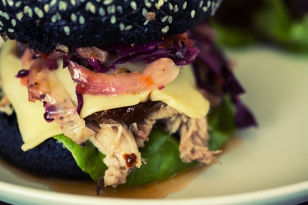 Pork hamburger made from bread Breeze Yacht mixing bamboo charcoal black. Served with salad and fried potato discs.の写真素材