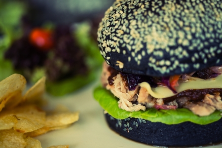 Pork hamburger made from bread Breeze Yacht mixing bamboo charcoal black. Served with salad and fried potato discs.の写真素材