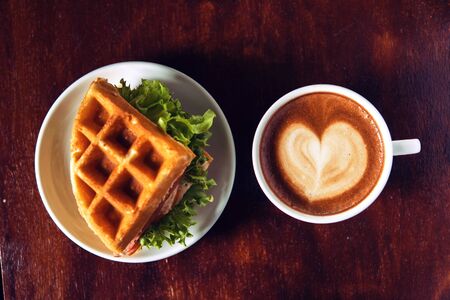 Ham and cheese sandwich served with hot coffee.on wooden table backgroundの写真素材