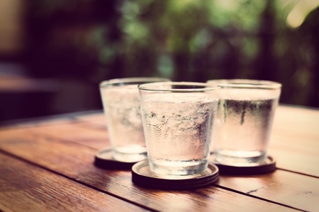 Drinking cold water into a  three glass placed on the wooden table.の写真素材