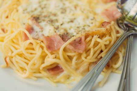 The spaghetti white sauce with bacon on a wooden table.