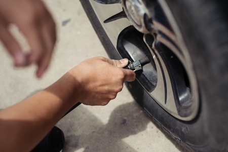 Man asia driver checking air pressure and filling air in the tires of carの写真素材