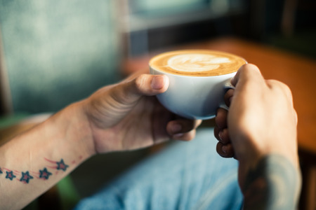 Coffee machine making coffee holded by tattooed barista armの写真素材