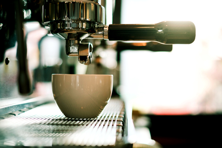 Coffee machine making coffee holded by tattooed barista armの写真素材