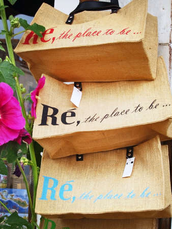 Ile de Re (Island of Re): Shopping bags in a souvenir shop with a Hollyhock flower on foreground (typical of the island)  in France, Atlantic ocean.の写真素材