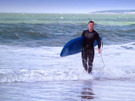 Surfer walking at the beach at the Atlantic ocean, France