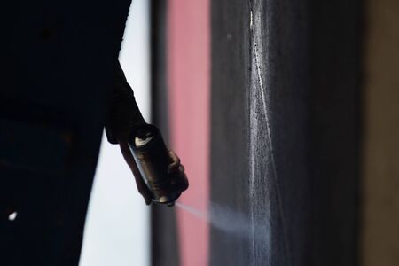 the process of creating graffiti is sprayed paint on the wall of the building from a containerの写真素材