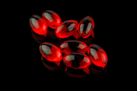 Red vitamin pills on black background. Selective focus limited to front pills.   の写真素材