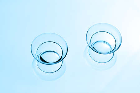 Two contact lenses with reflections on a blue background.の写真素材