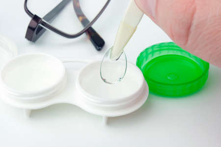 Contact lens, eyeglasses, case and tweezers on grey background. Selective focus on contact lens.の写真素材