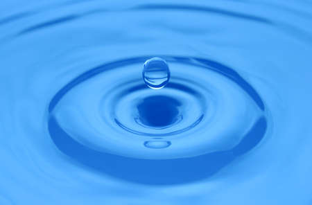Water drop close up on a blue surface. Abstract backgrpound. Shallow DOF.
