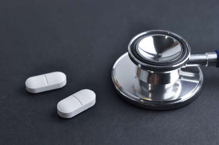 Stethoscope and Medication on a black surface. Diagnosic and Treatment concept.の写真素材
