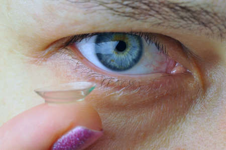 Woman holding contact lens near her eye. Closeup image. Focus on eye.の写真素材
