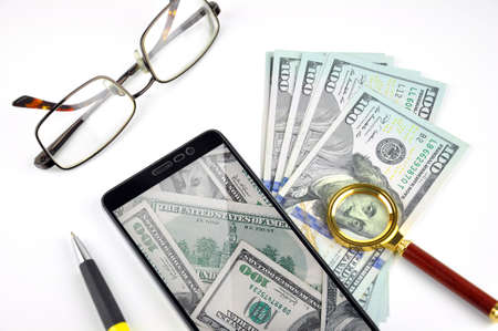 Smartphone, eyeglasses, pen, magnifying glass and the money. Analysis and Success concept. Profit from e-commerce. Businessman workplace.の写真素材