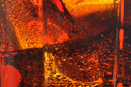Cola in glass with ice and a bubbles of gas. Macro photo.