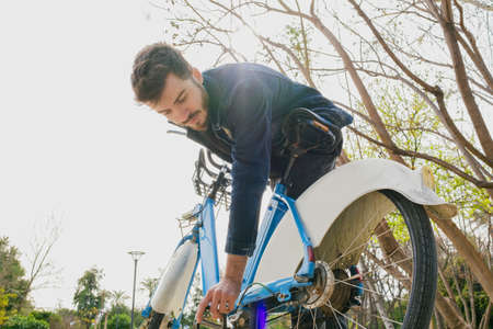 Bicycle repair, young man trying to fix his broken bike, he is stuck on the road and is trying to get out of this situation on his ownの写真素材
