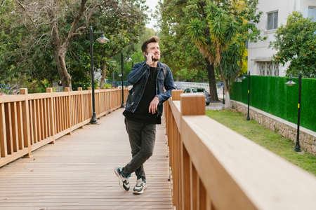 Walking, young man is walking in a green park with his hands in his pockets, a handsome adult...