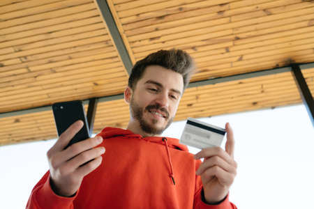 Internet shopping, young man is experiencing happiness after secure online shopping, he waves his credit card and smiles, facial expression and enjoymentの写真素材