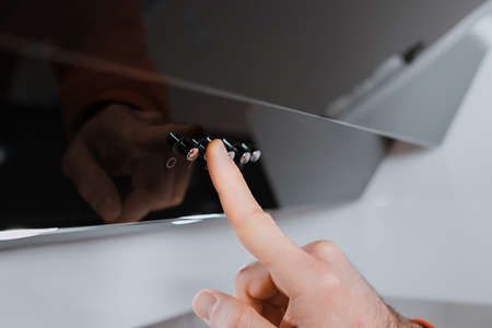 Young man checking, measuring blood pressure with digital tonometer at home holding medical electronic device.の写真素材