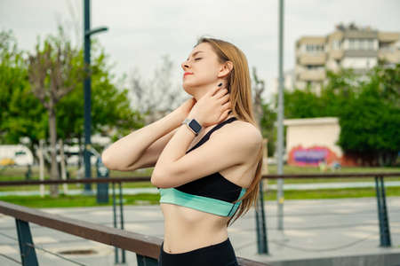 Young caucasian woman wearing black sports bra standing on city park, outdoors relaxing with eyes closed, feeling alive, breathing, dreaming.の写真素材