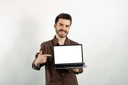 Happy casual man wearing casual clothes posing isolated over white background pointing with index...