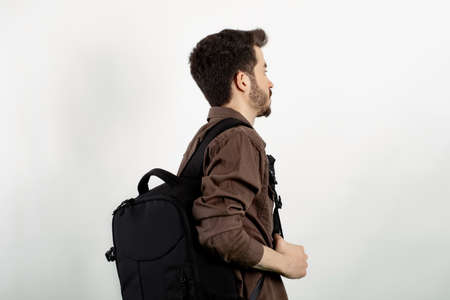 Young man wearing brown shirt posing isolated over white background student wearing a backpack with...