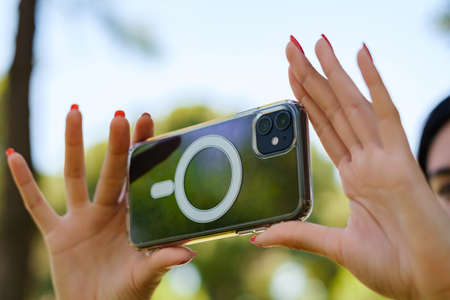 Young caucasian woman wearing tee standing on city park, outdoors taking horizontal photo with her...