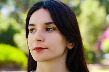Young caucasian woman wearing tee standing on city park, outdoors thinking of problems and feeling...