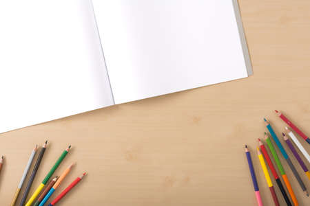 Colour pencils on the wood texture table with white artbookの写真素材