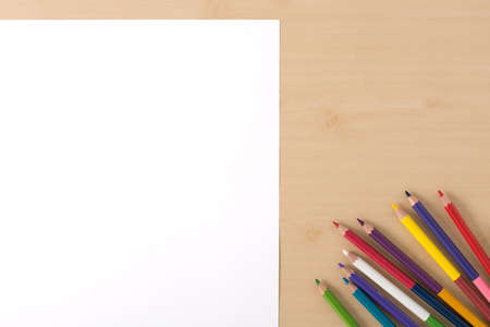 Multiple colour pencils on the  wood texture table with white papersの写真素材