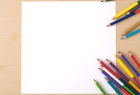 Multiple colour pencils on the  wood texture table with white papersの写真素材