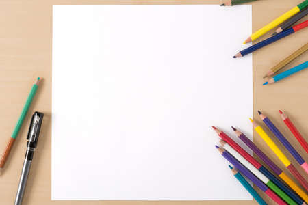 Multiple colour pencils on the  wood texture table with white papersの写真素材