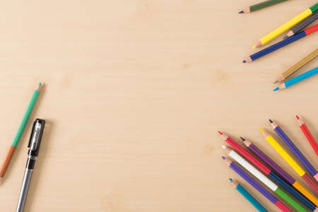 Multiple colour pencils and pen on the  wood texture tableの写真素材