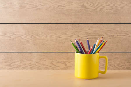 Yellow cup with colour pencil on wood textureの写真素材
