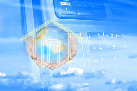 hands keeps globe and drawing house on background of the keyboard of the telephoneの写真素材