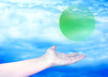 feminine hand and green ball on background sky and cloud