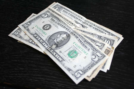 paper dollar bills resting upon dark background