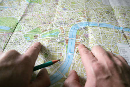 hand with pencil and geographical card to terrain